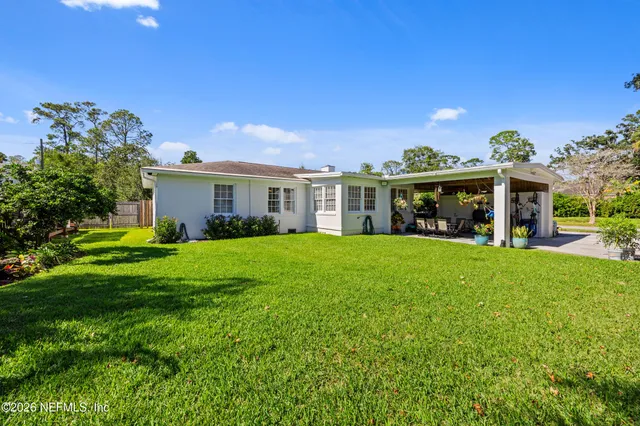a view of house with a big yard and potted plants
