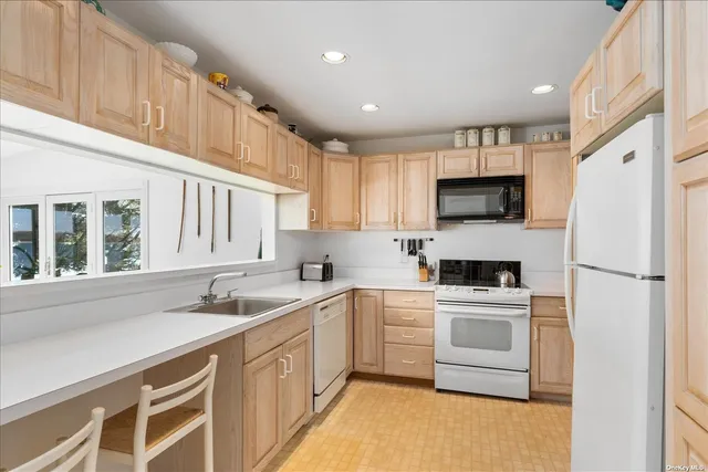a kitchen with a sink white cabinets and white appliances