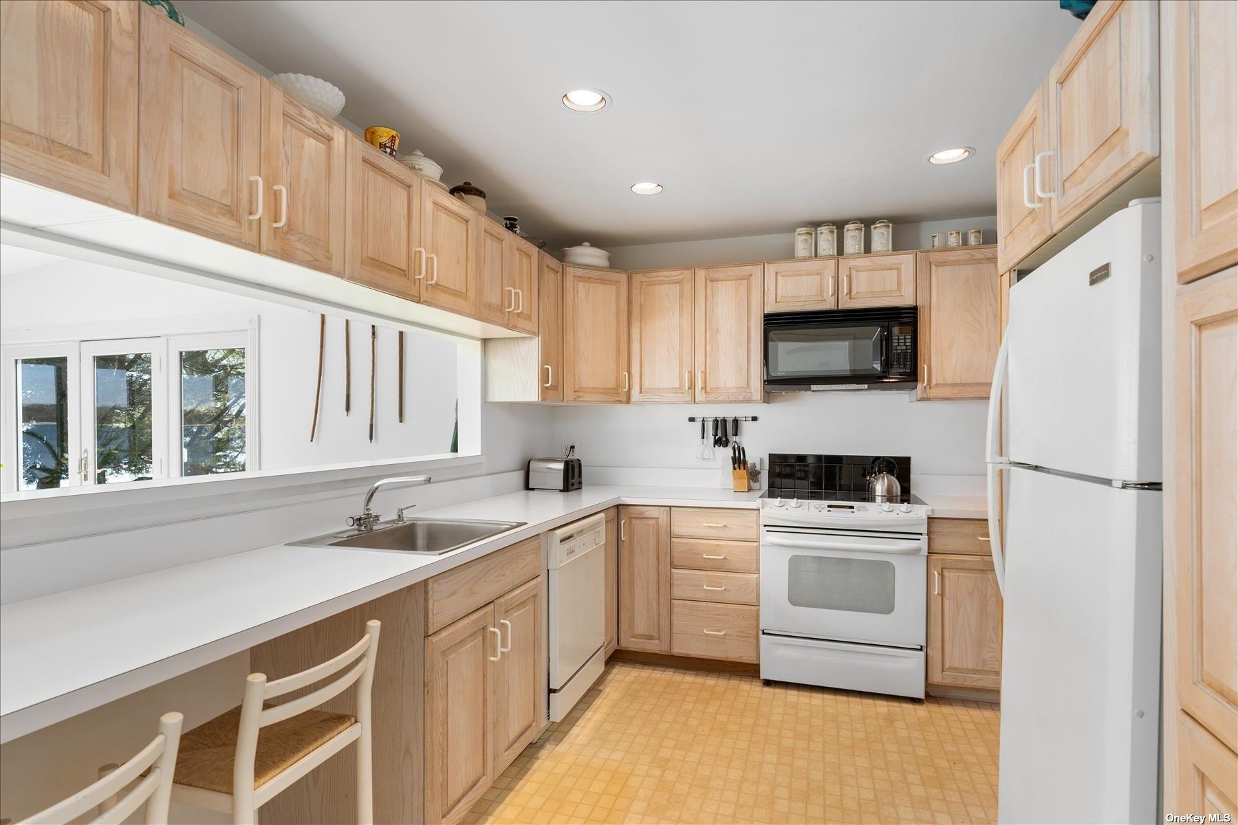 1155 Old Harbor Road New Suffolk, NY 11956 - Photo 12 of 21 a kitchen with a sink white cabinets and white appliances