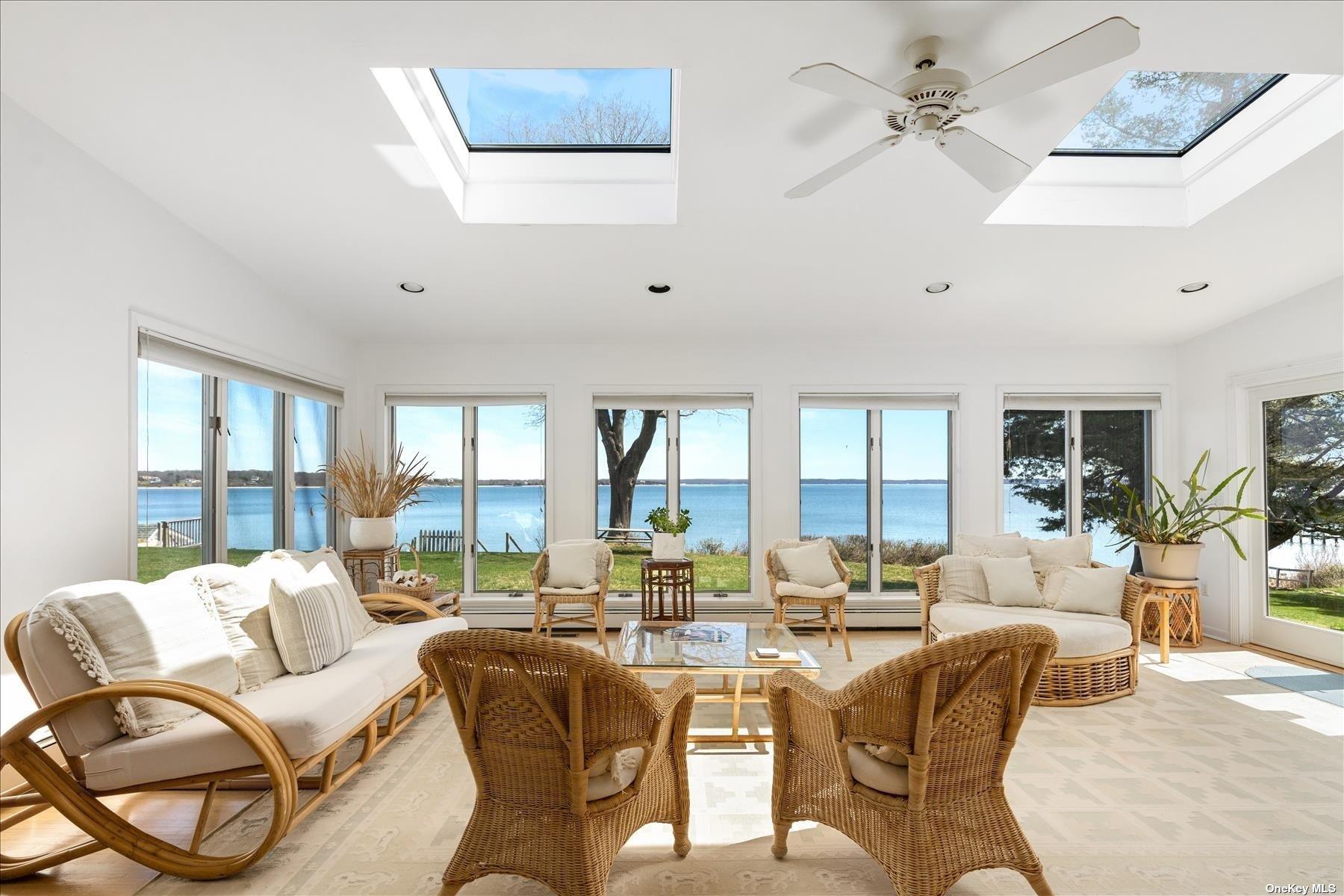 1155 Old Harbor Road New Suffolk, NY 11956 - Photo 7 of 21 a living room with furniture large windows and a chandelier