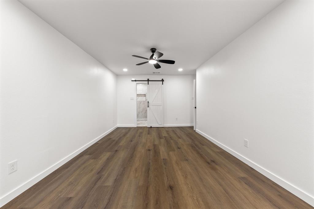 3227 Mayhew Drive Dallas, TX 75228 - Photo 15 of 25 an empty room with wooden floor ceiling fan and windows