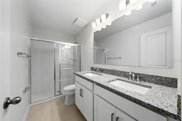 a bathroom with a granite countertop sink a toilet a mirror and shower