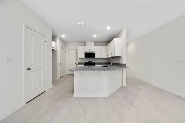 a view of kitchen with granite countertop cabinets and refrigerator