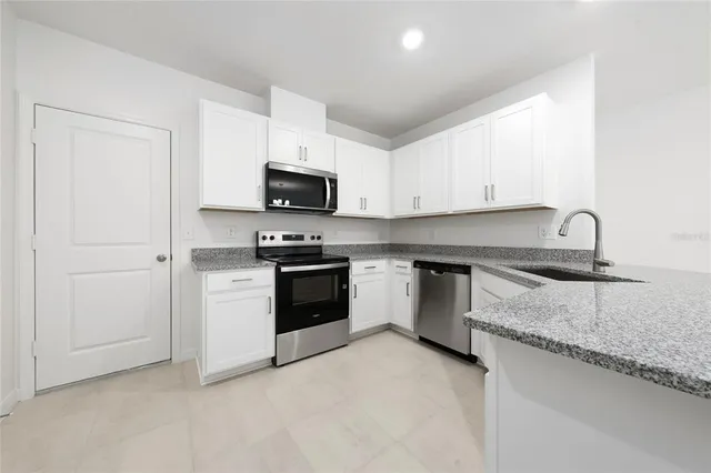 a kitchen with granite countertop a sink a stove and cabinets