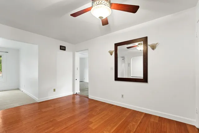 a view of an empty room with a window and wooden floor