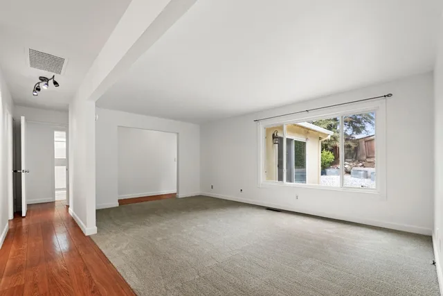 a view of an empty room with a window and wooden floor