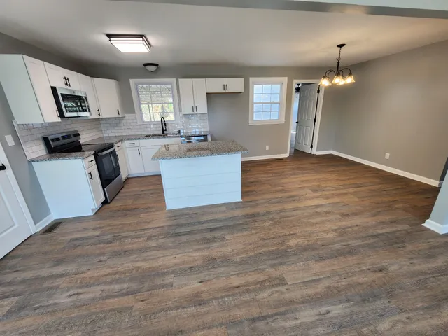 a kitchen with granite countertop a stove top oven a sink dishwasher and a refrigerator with wooden floor