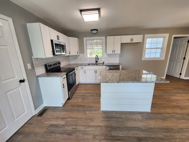 a large kitchen with cabinets wooden floor and stainless steel appliances