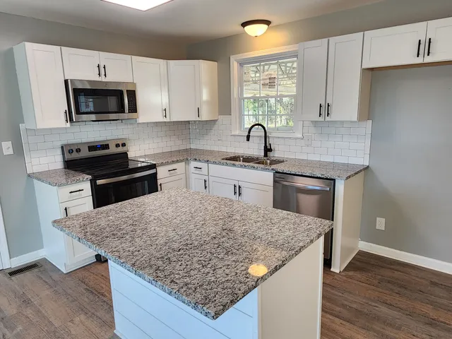 a kitchen with kitchen island granite countertop a stove sink and microwave