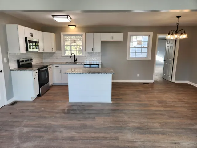 a kitchen with granite countertop a stove a sink and a refrigerator