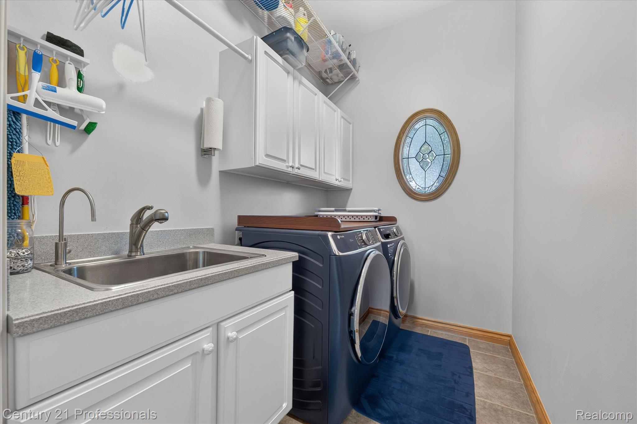 5675 36 Mile Road Romeo, MI 48065 - Photo 25 of 54 Utility room featuring a large built-in sink with a gooseneck faucet, white cabinetry, and a countertop with speckled finish- storage shelf above
