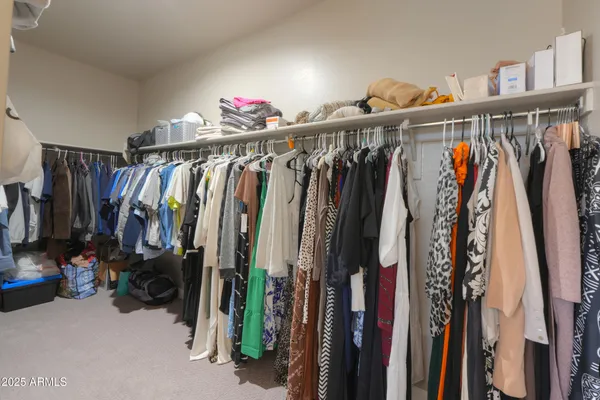 a view of walk in closet with clothes and shoes