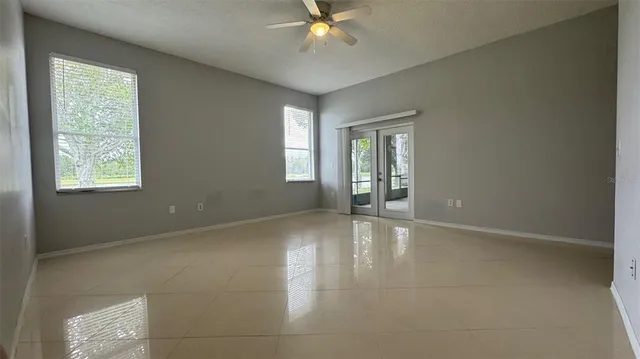 a view of an empty room with window and wooden floor