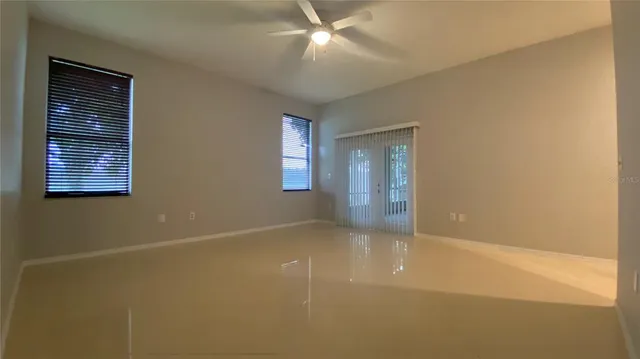 a view of an empty room with chandelier fan and a window