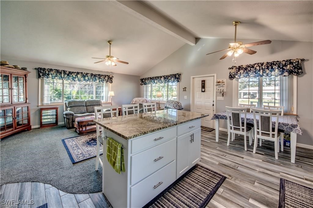 10796 Russell Road Bokeelia, FL 33922 - Photo 12 of 47 an open kitchen with granite countertop a stove dining table chairs and a chandelier