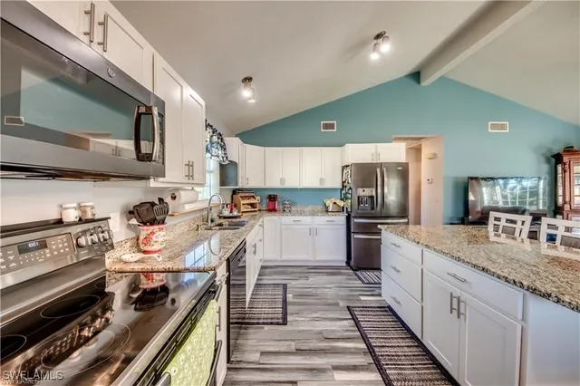 a large kitchen with stainless steel appliances kitchen island granite countertop a stove and a sink