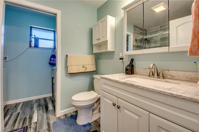 a bathroom with a granite countertop sink a toilet and a mirror