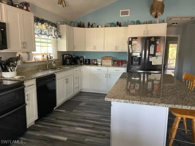 a kitchen with granite countertop a stove a sink a microwave and wooden cabinets