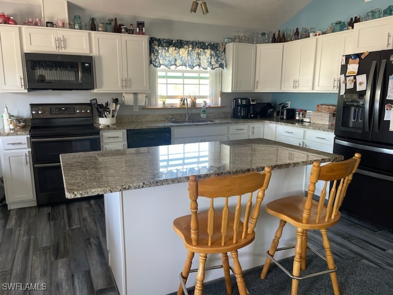 10796 Russell Road Bokeelia, FL 33922 - Photo 23 of 47 a kitchen with granite countertop a stove a sink a microwave and wooden cabinets