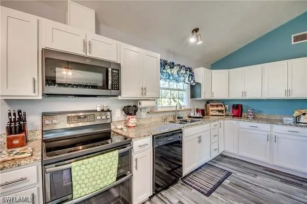 a kitchen with stainless steel appliances white cabinets granite counter tops and a window