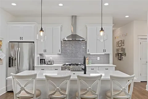 a kitchen with stainless steel appliances kitchen island granite countertop a refrigerator a stove a kitchen island with a dining table and chairs