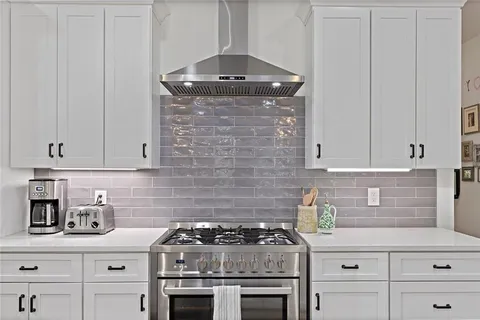a kitchen with granite countertop a stove top oven a sink and cabinets