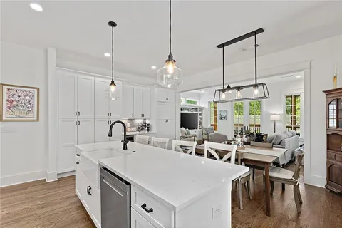 a kitchen with sink stove and white cabinets with wooden floor