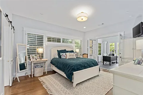a living room with a bed furniture flat screen tv and large windows