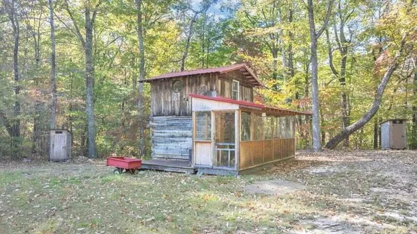 a view of a small barn in the middle of forest