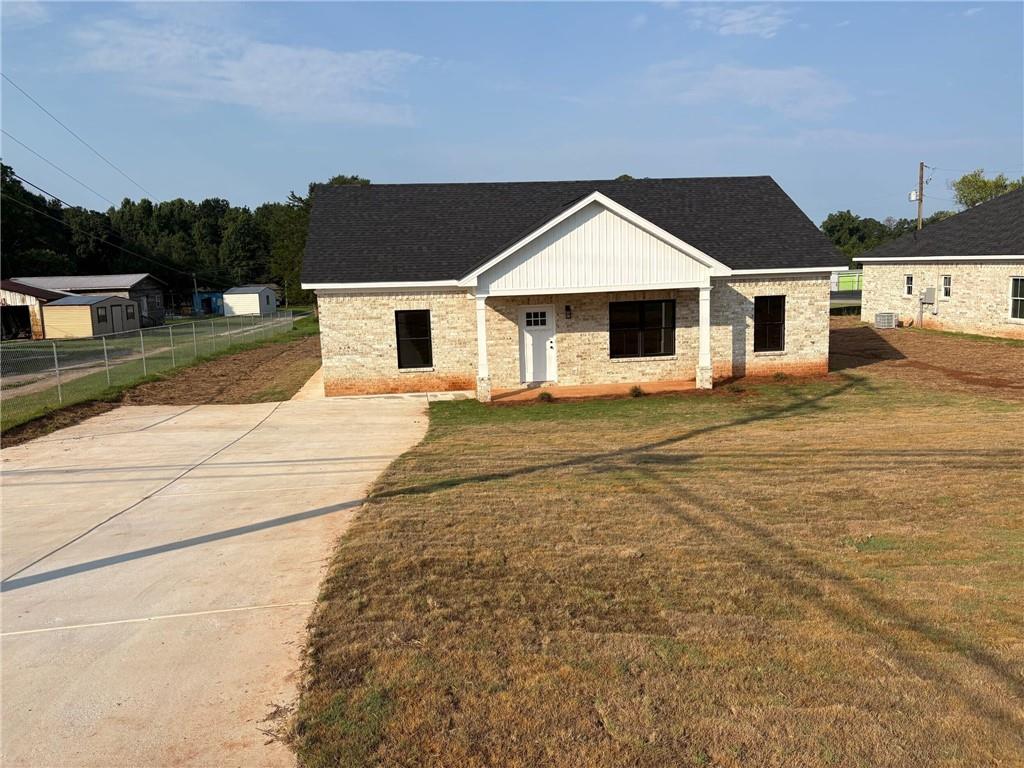 3216 South Phillips Road Lanett, AL 36863 - Photo 2 of 14 Single-story residence featuring light-colored brick veneer, a dark shingle roof, and a prominent front gable with vertical white siding