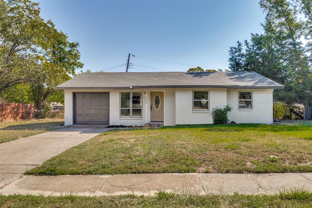 Single story home with a front yard, driveway, brick siding, roof with shingles, and an attached garage
