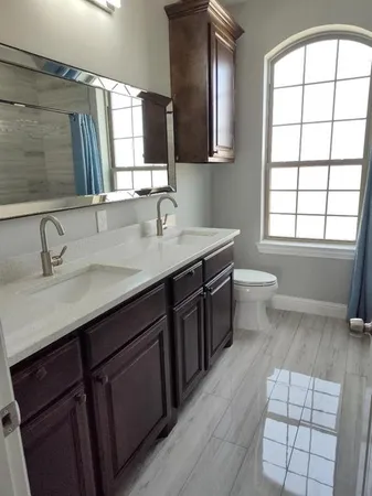 a bathroom with a double vanity sink a toilet and a mirror