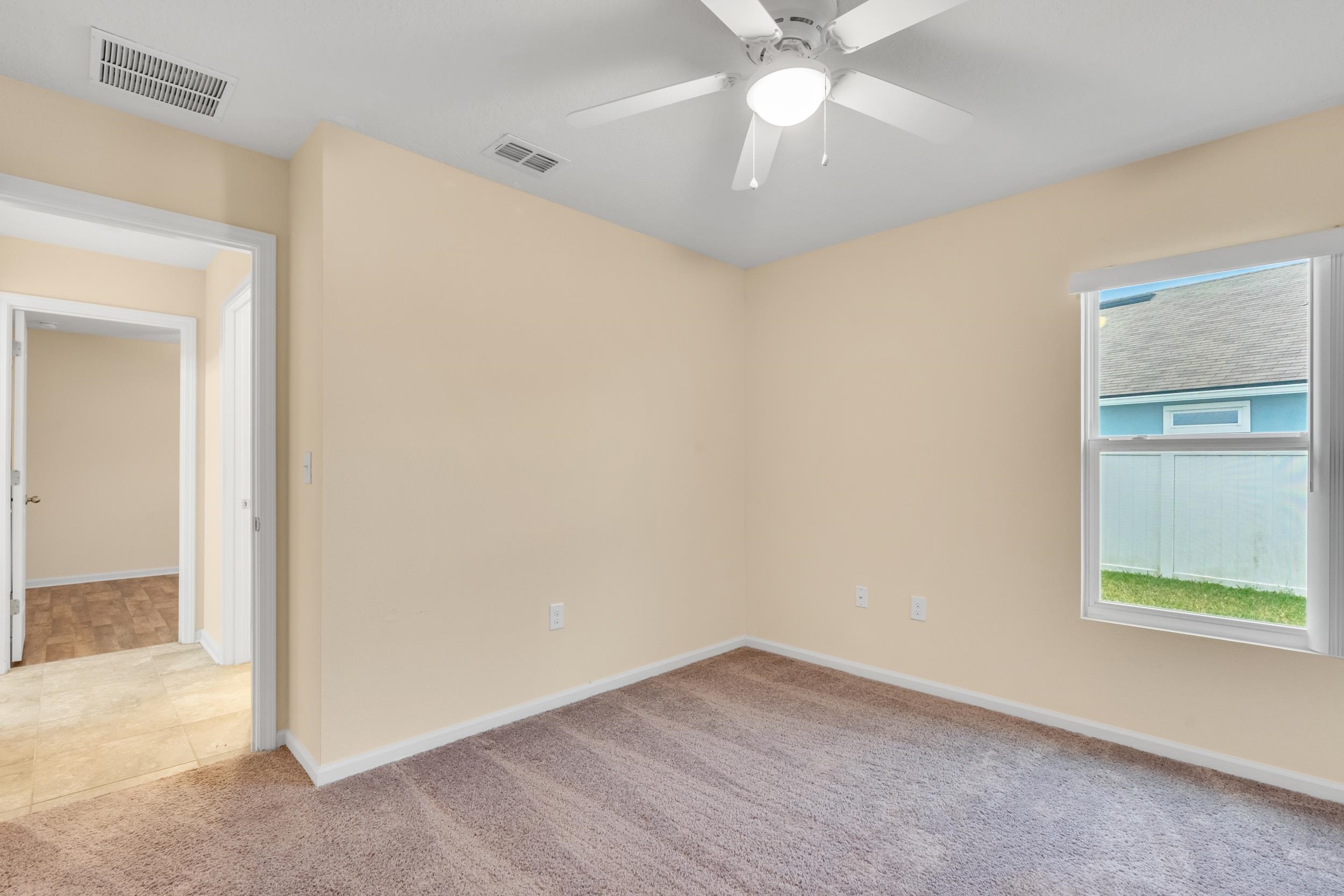 228 Fox Water Trail St. Augustine, FL 32086 - Photo 19 of 50 an empty room with a chandelier fan and windows