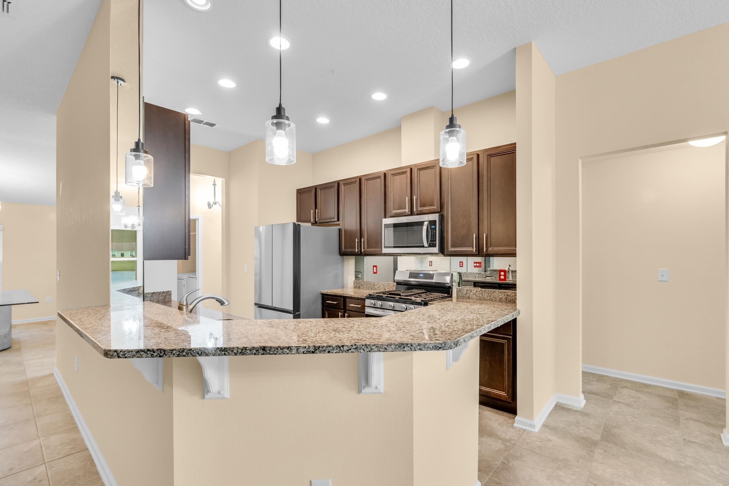228 Fox Water Trail St. Augustine, FL 32086 - Photo 23 of 50 a kitchen with kitchen island granite countertop stainless steel appliances a sink stove and refrigerator