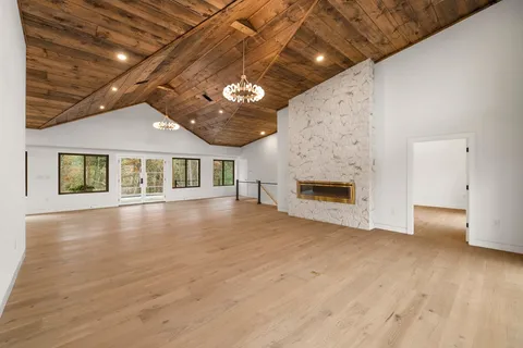a view of an empty room with a fireplace and wooden floor