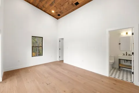 a view of an empty room with wooden floor and a bedroom