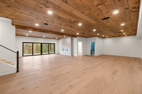a view of an empty room with wooden floor and windows