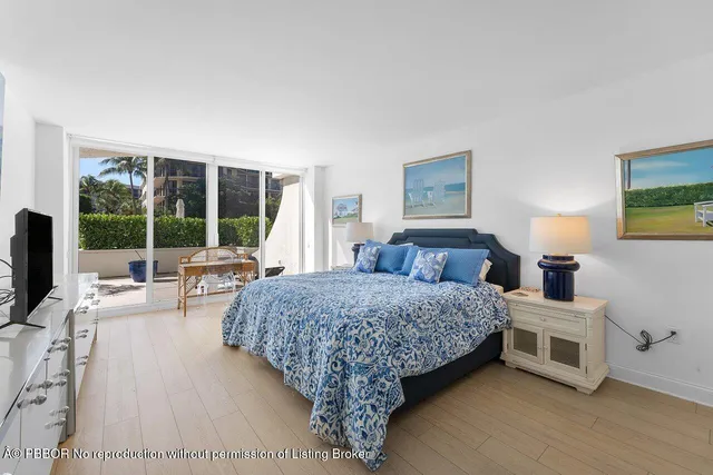 a living room with a bed furniture large window and a flat tv screen