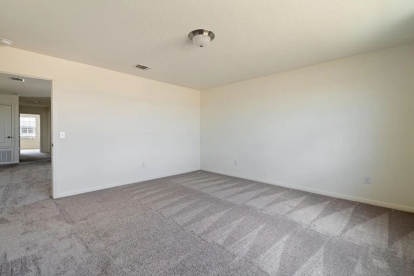 101 Aoudad Road Hutto, TX 78634 - Photo 33 of 39 An inviting room awaits personalization, featuring soft gray carpet and pristine white walls.