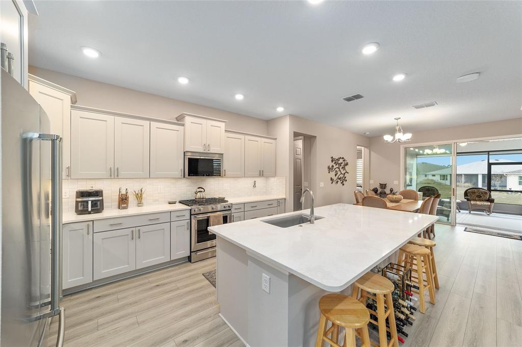 10691 Southwest 99th Place Ocala, FL 34481 - Photo 16 of 52 a large kitchen with kitchen island a sink a stove a refrigerator and white cabinets with wooden floor