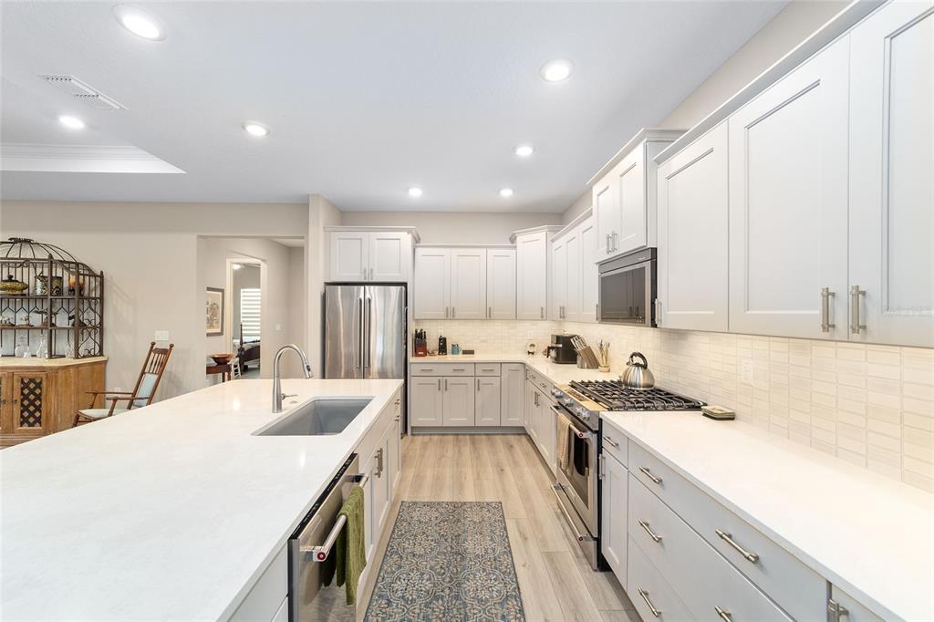 10691 Southwest 99th Place Ocala, FL 34481 - Photo 17 of 52 a large kitchen with kitchen island a stove a sink a refrigerator and white cabinets with wooden floor