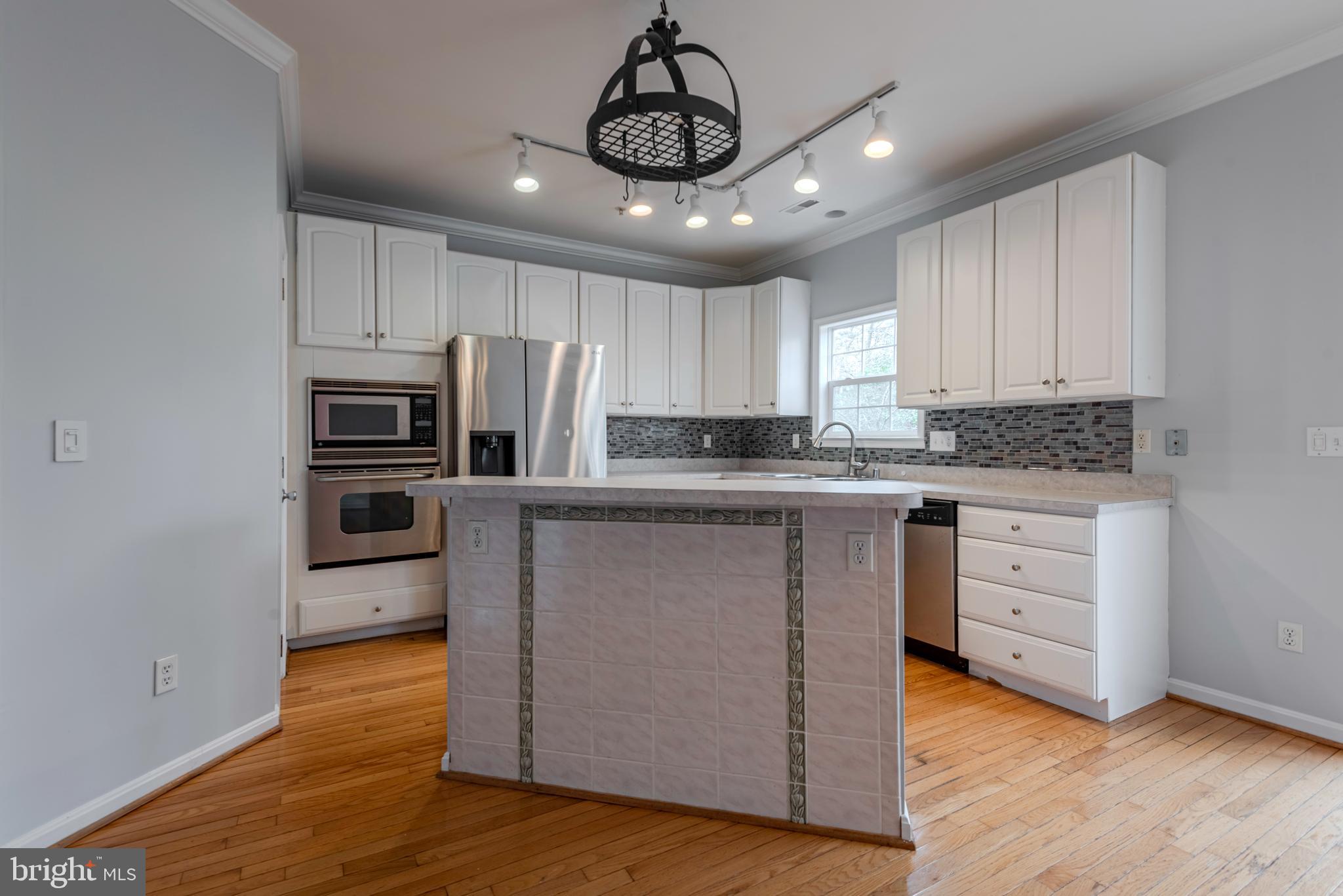 226 Wintergull Lane Annapolis, MD 21409 - Photo 11 of 38 a kitchen with stainless steel appliances granite countertop a refrigerator a stove top oven a sink and dishwasher with wooden floor