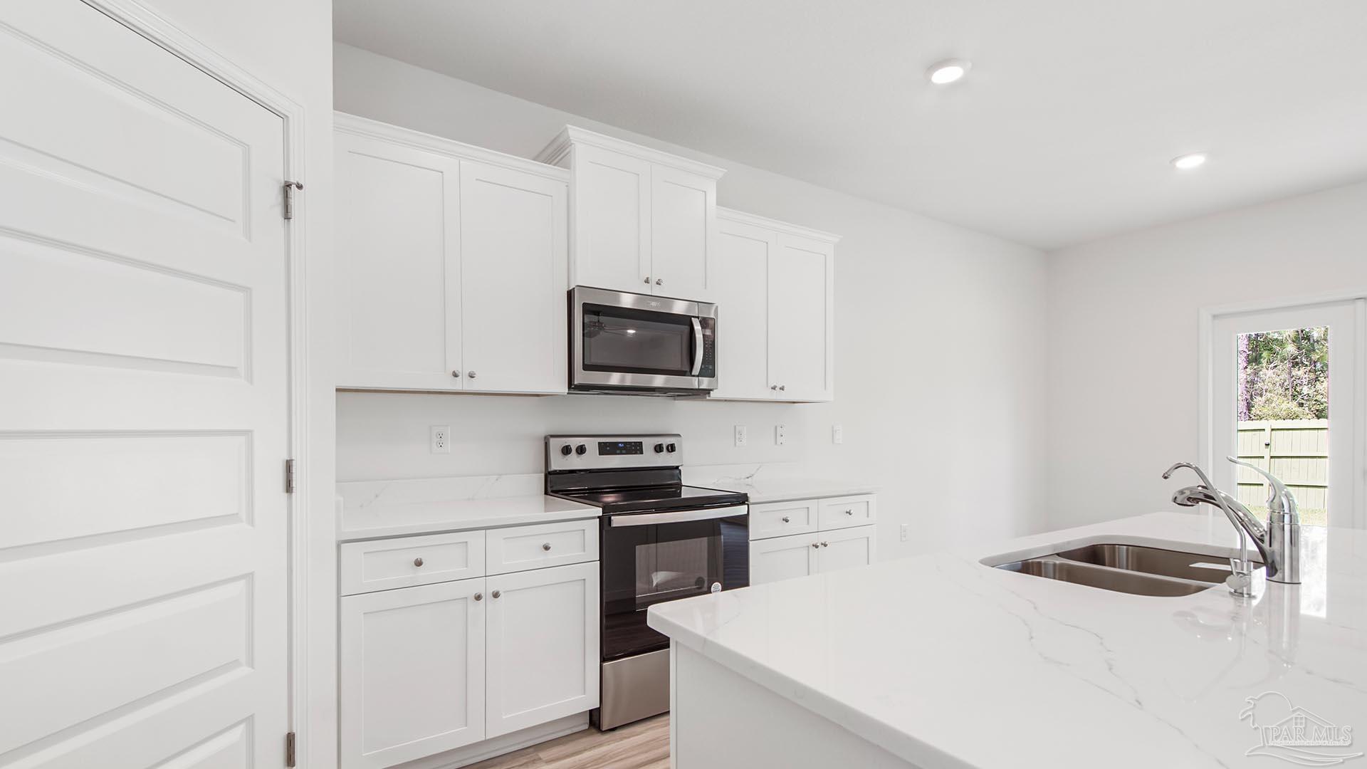 3233 Harrier Road Pace, FL 32571 - Photo 33 of 50 a kitchen with white cabinets and stainless steel appliances