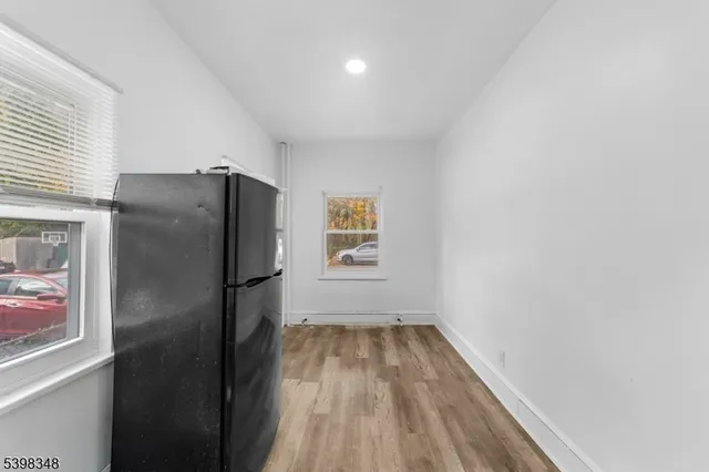 a view of a refrigerator in kitchen and an empty room