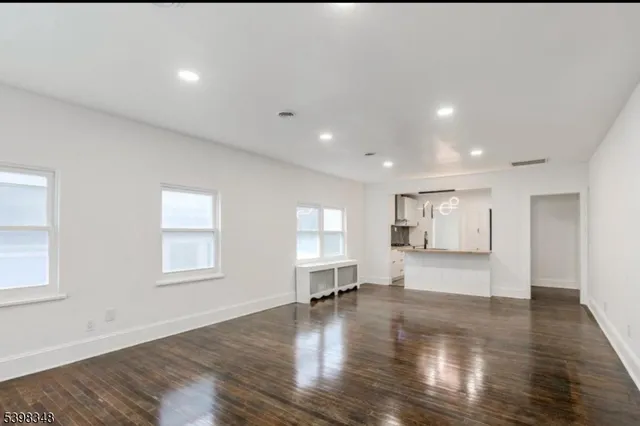 a view of empty room with wooden floor and windows