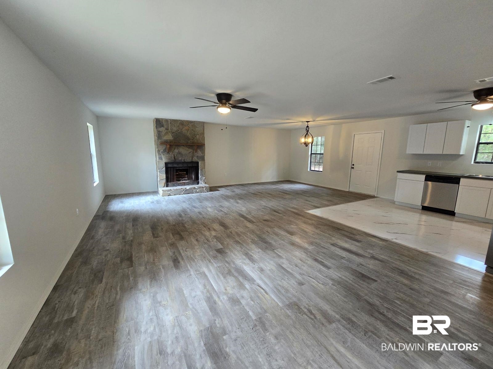 1600 Blair Road Brewton, AL 36426 - Photo 4 of 15 Unfurnished living room featuring ceiling fan with notable chandelier, a fireplace, and hardwood / wood-style floors