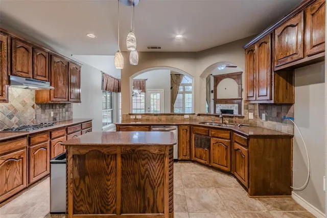 a kitchen with stainless steel appliances granite countertop a sink a stove and a wooden cabinets