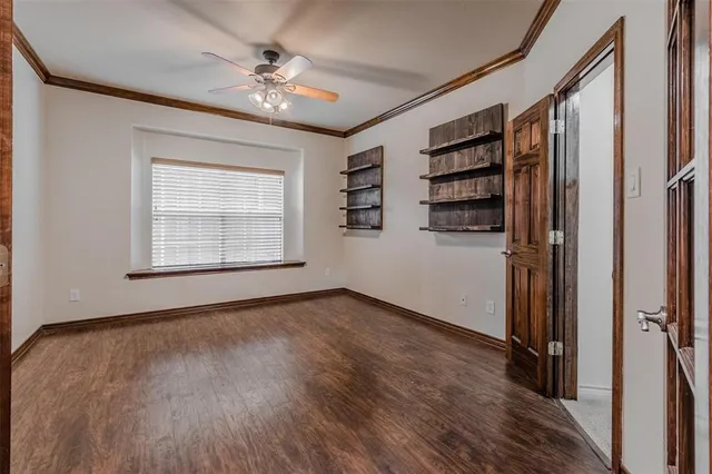 an empty room with wooden floor closet and windows