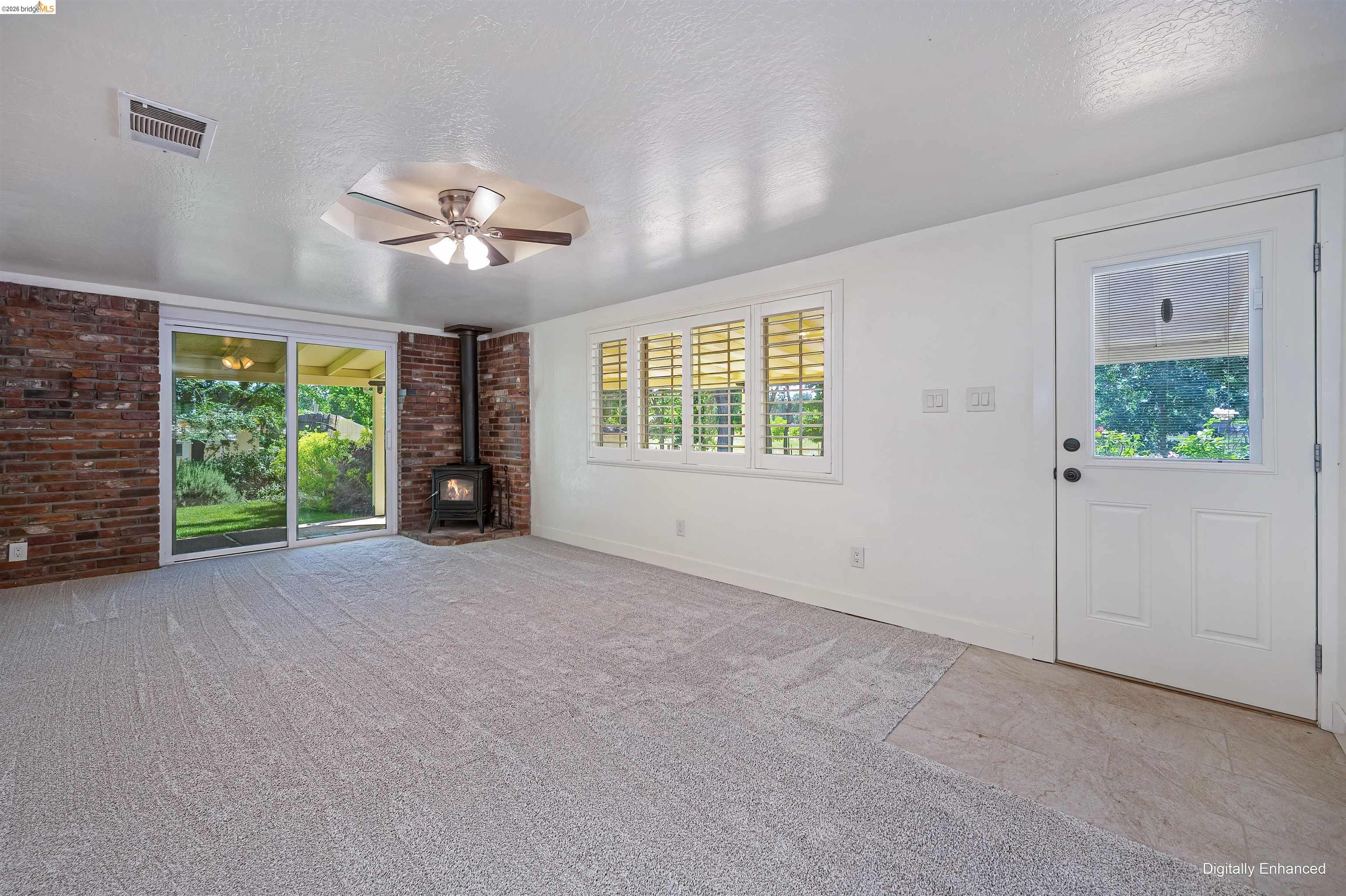 10474 Sheldon Road Elk Grove, CA 95624 - Photo 10 of 83 Spacious interior with light-toned carpet flooring, a brick accent wall, and a freestanding wood-burning stove