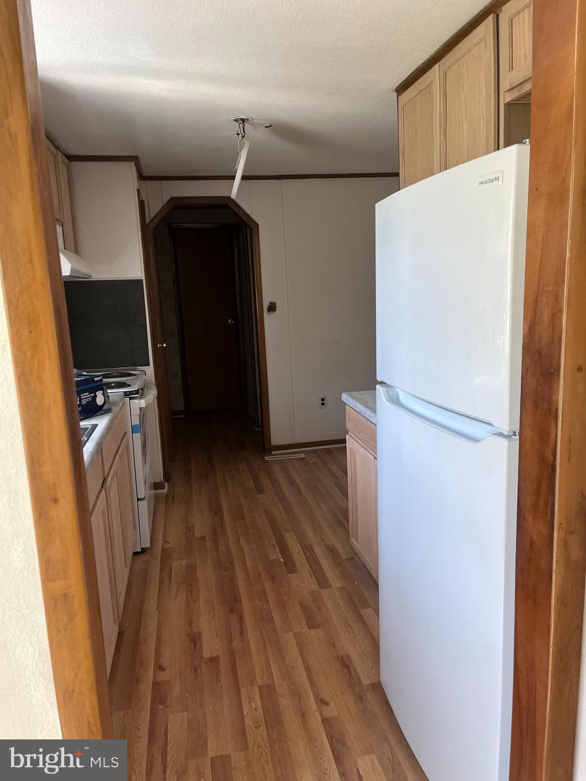 369 Ivey Creek Road Lancaster, VA 22503 - Photo 20 of 31 a view of a refrigerator in kitchen and an empty room with wooden floor